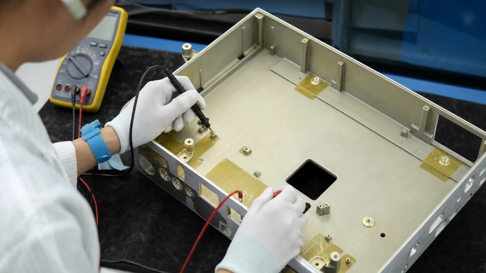Chemical conversion coated aluminum chassis with masked grounding areas inspected by technician