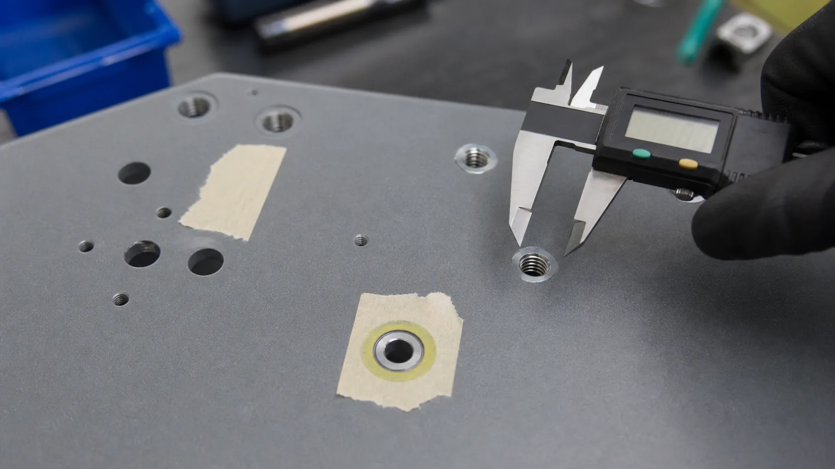 Powder-coated enclosure holes and masked grounding pads checked with digital calipers