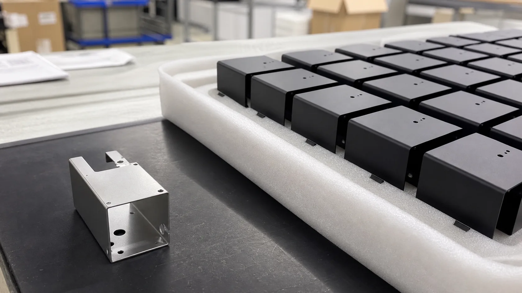 Prototype sheet metal part compared with larger powder-coated enclosure batch